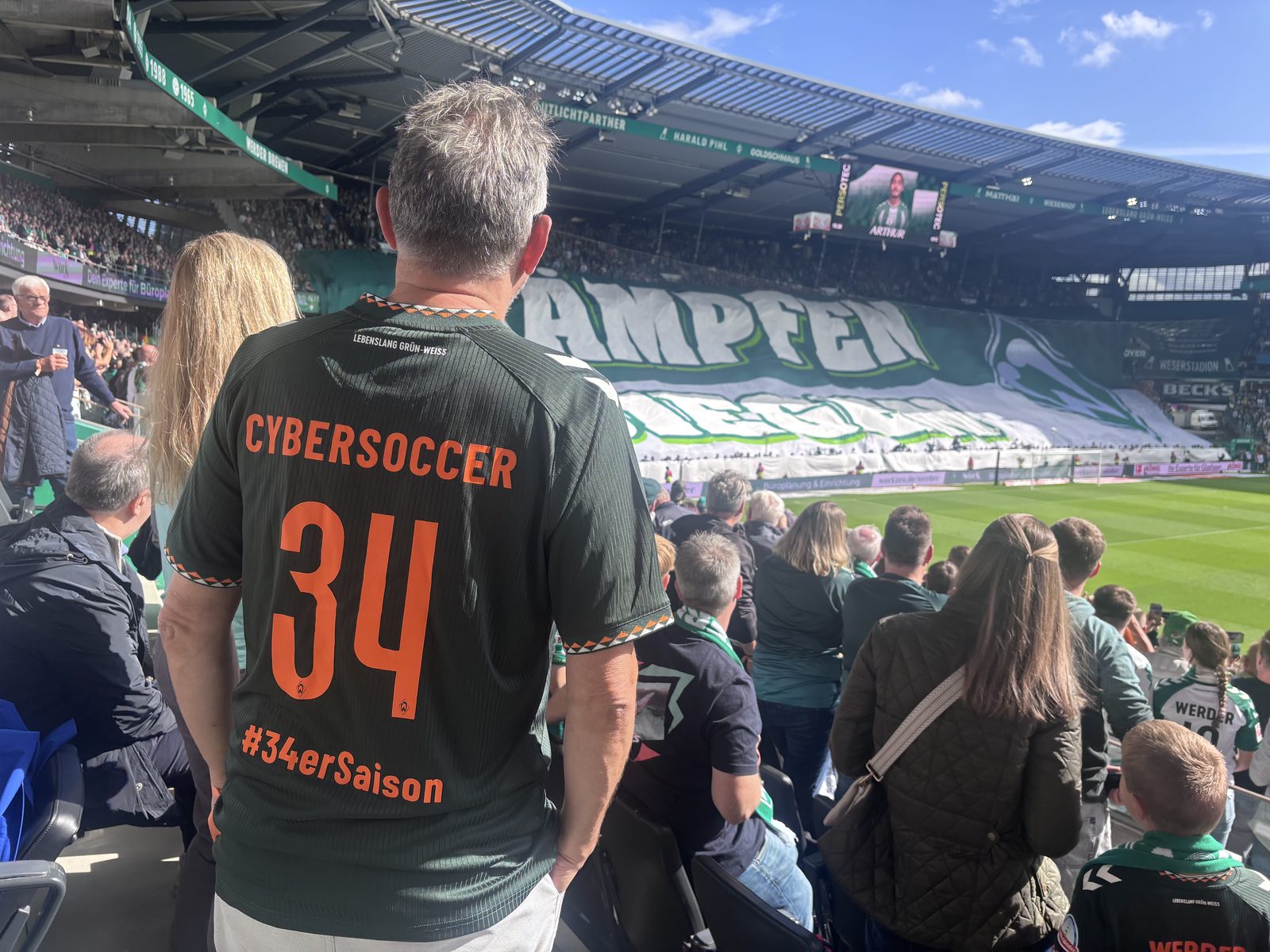 Trikot-Rücken mit der Aufschrift CYBERSOCCER 34 und #34erSaison vor der Blockfahne der Ostkurve im Weserstadion.