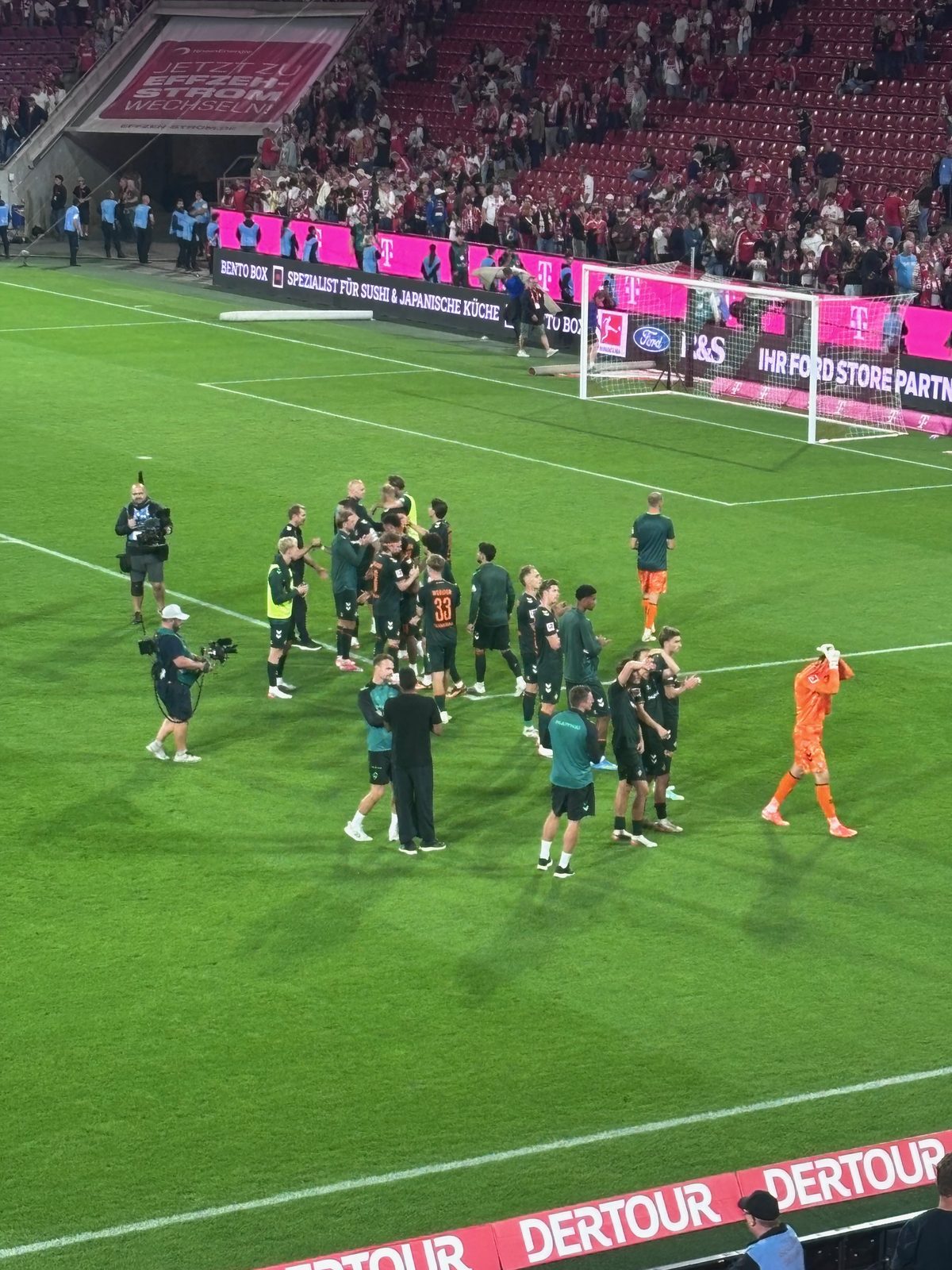 Die Werder-Mannschaft steht nach dem Abpfiff auf dem Rasen des RheinEnergieStadions und bedankt sich in Richtung des Gästeblocks.