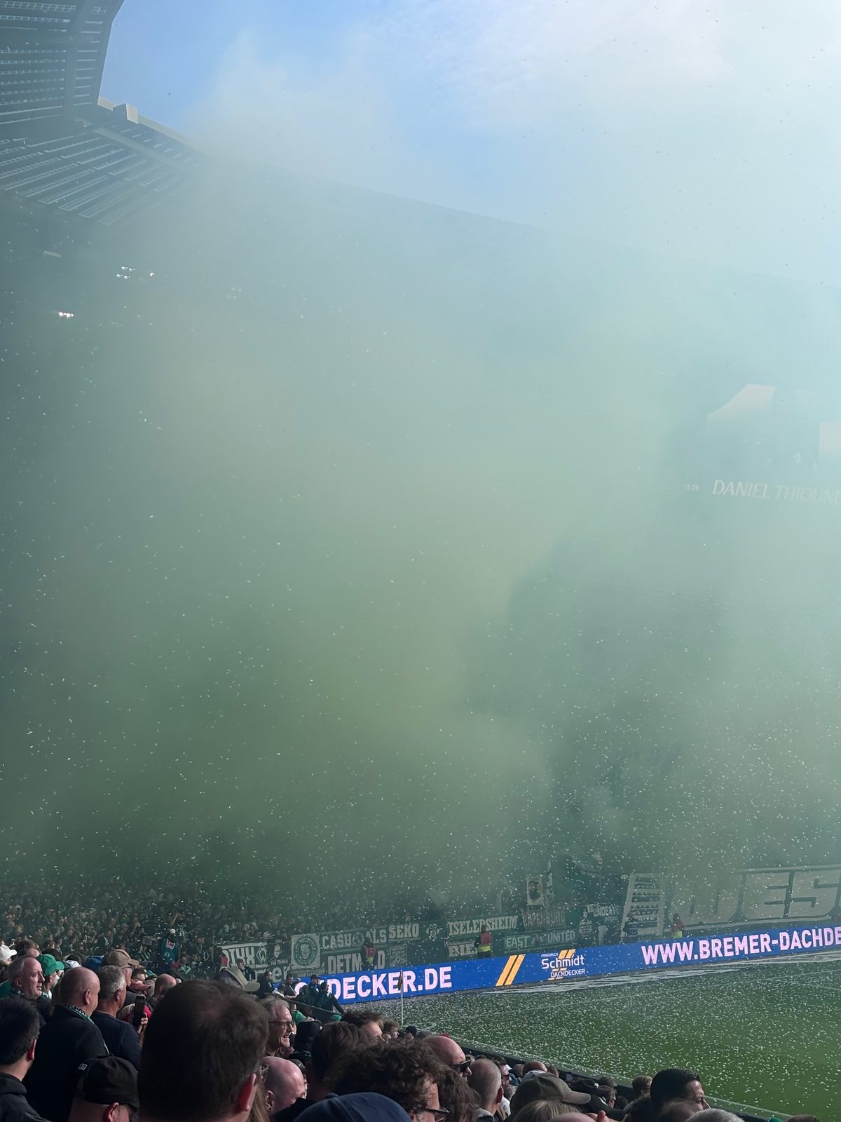 Dichter grünlicher Nebel füllt das Bild, von der Ostkurve ist nichts mehr zu erkennen. Nur unten schimmern Werbebanden, der Rasen und die Köpfe der Zuschauer im Vordergrund durch.