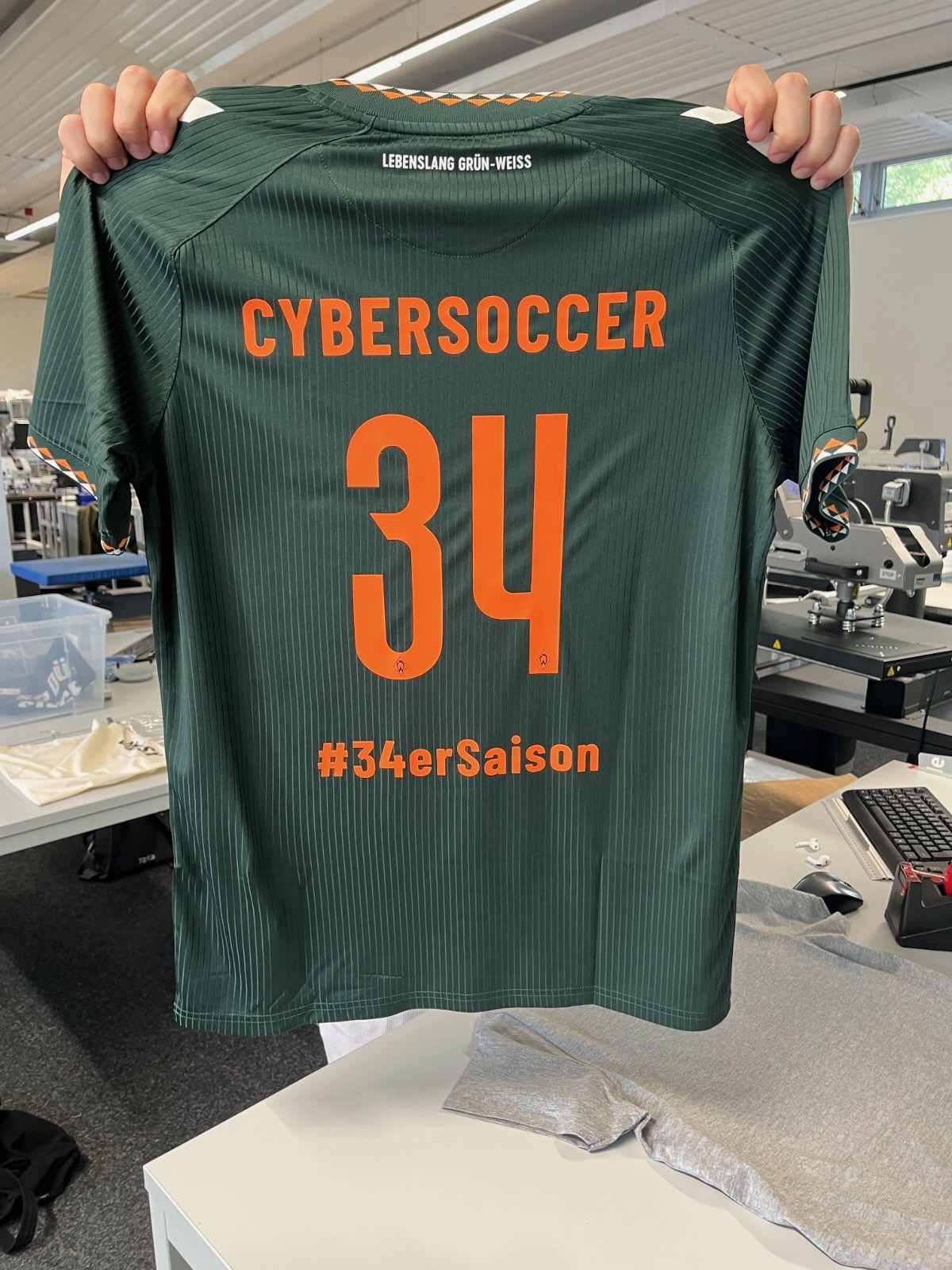 Werder-Trikot mit der Beflockung CYBERSOCCER, der Nummer 34 und #34erSaison, frisch in der Fan12-Werkstatt bedruckt.